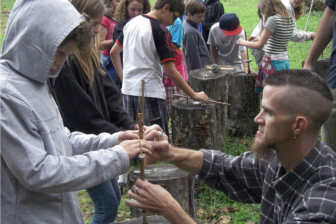 A student learns to use a Native American hand drill at the Living Archaeology Weekend. 